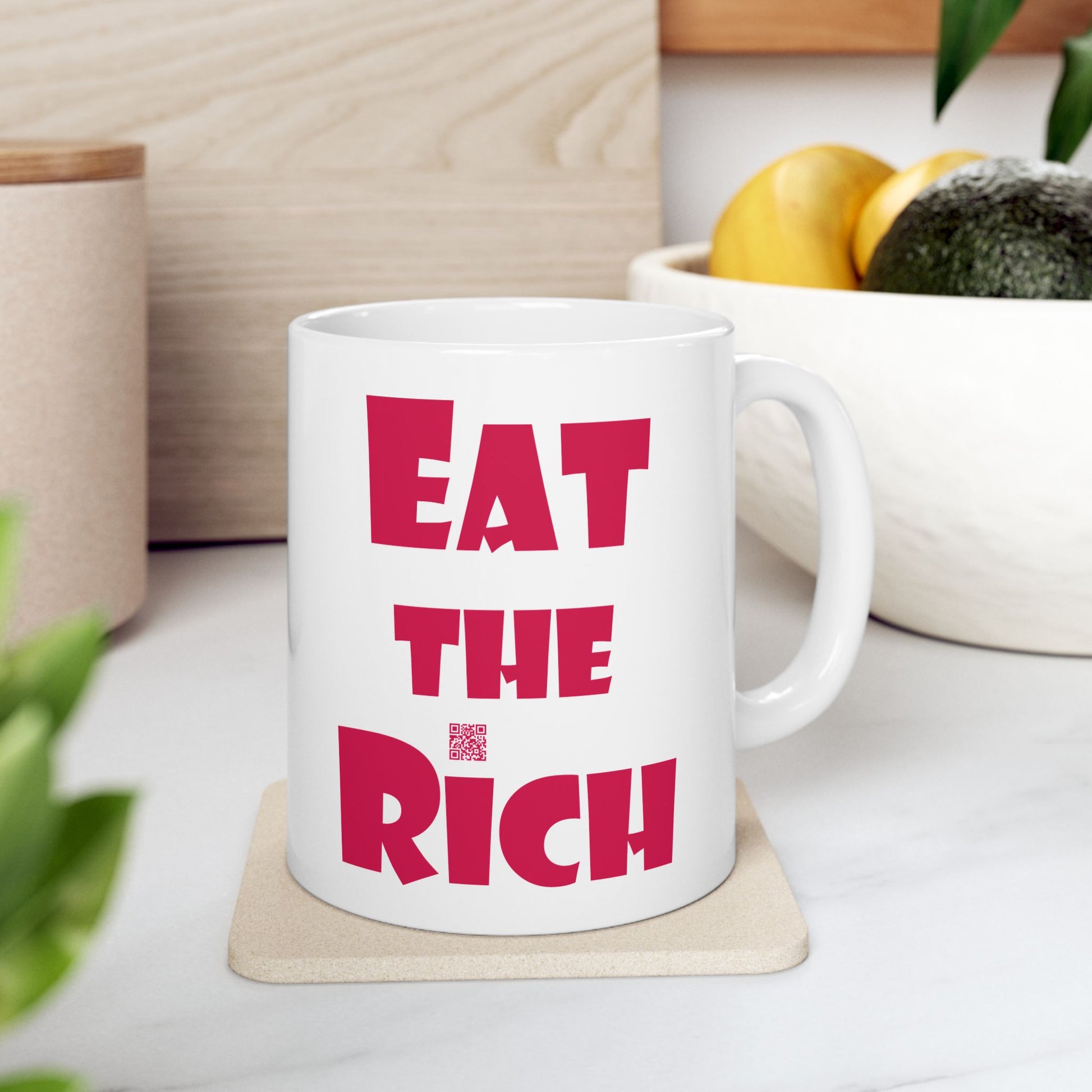 White EAT THE RICH 11oz Ceramic Mug with bold red text on a kitchen counter.
