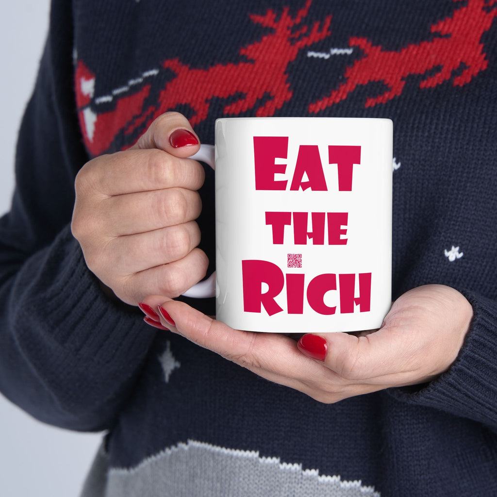 White EAT THE RICH 11oz Ceramic Mug held by a person wearing a festive sweater.