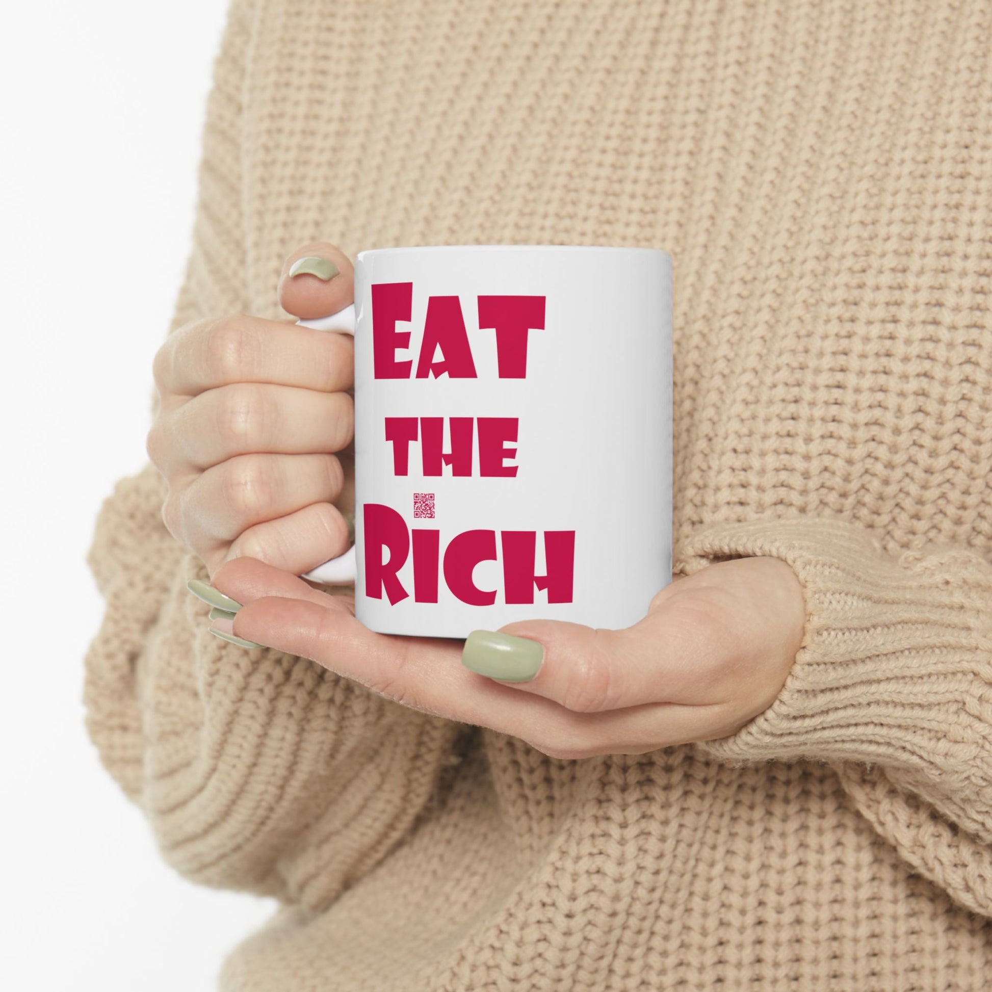 White EAT THE RICH 11oz Ceramic Mug held by a person in a cozy sweater, showcasing bold red text.