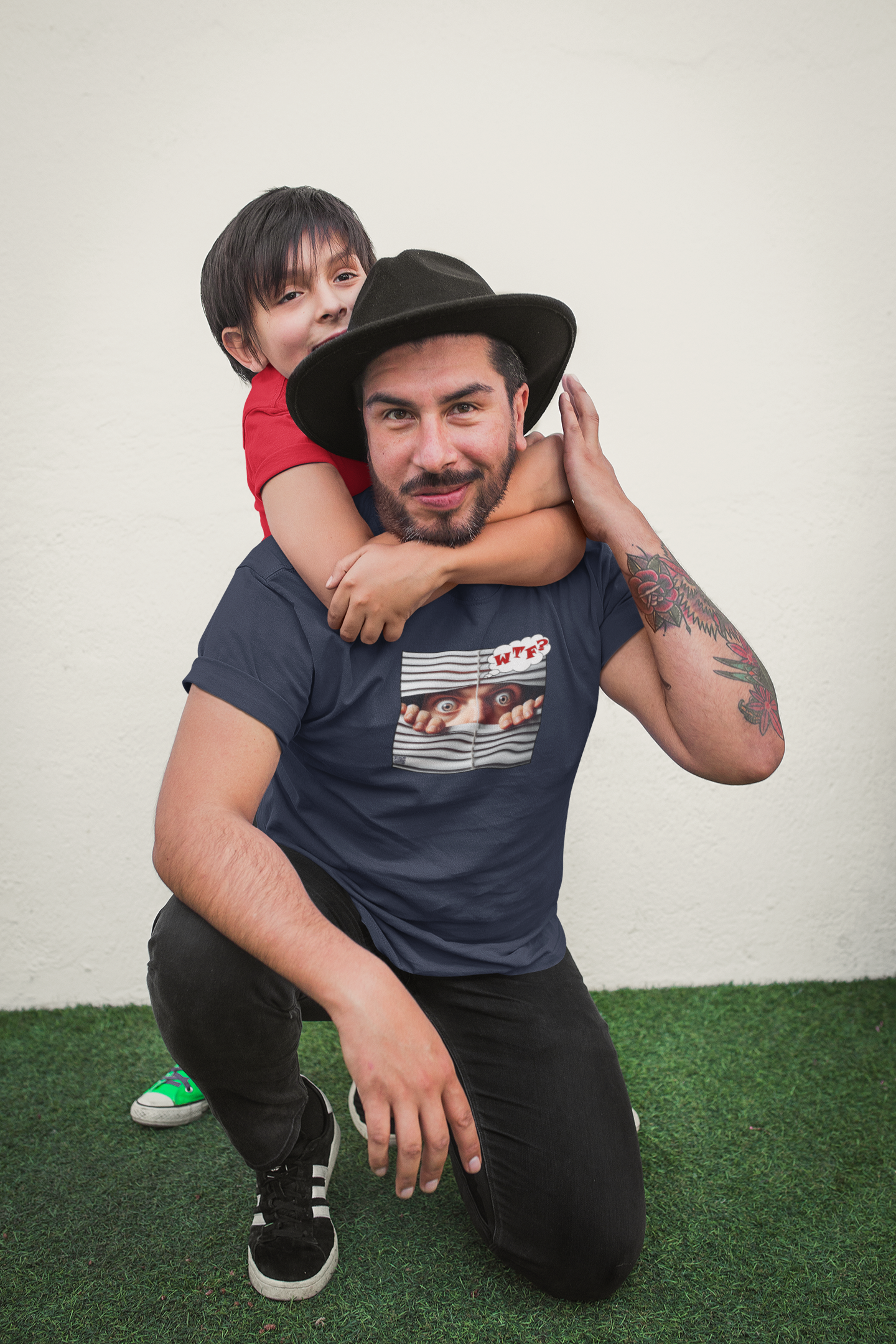 A man wearing a WTF White Male Model Activist Tshirt poses with a child, smiling outdoors.