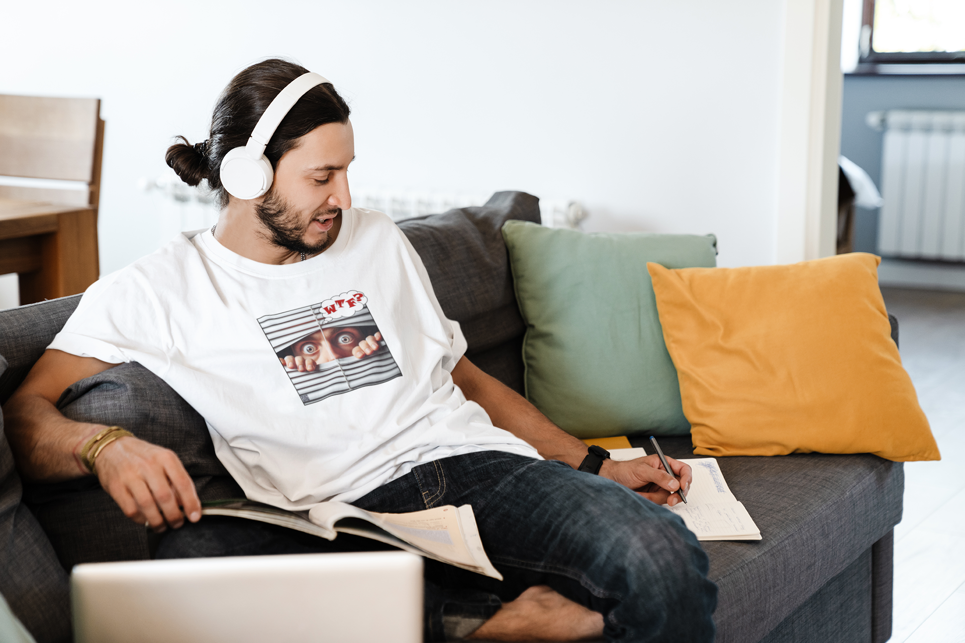 Man wearing WTF White Male Model Activist Tshirt studying and listening to music at home on a cozy couch.
