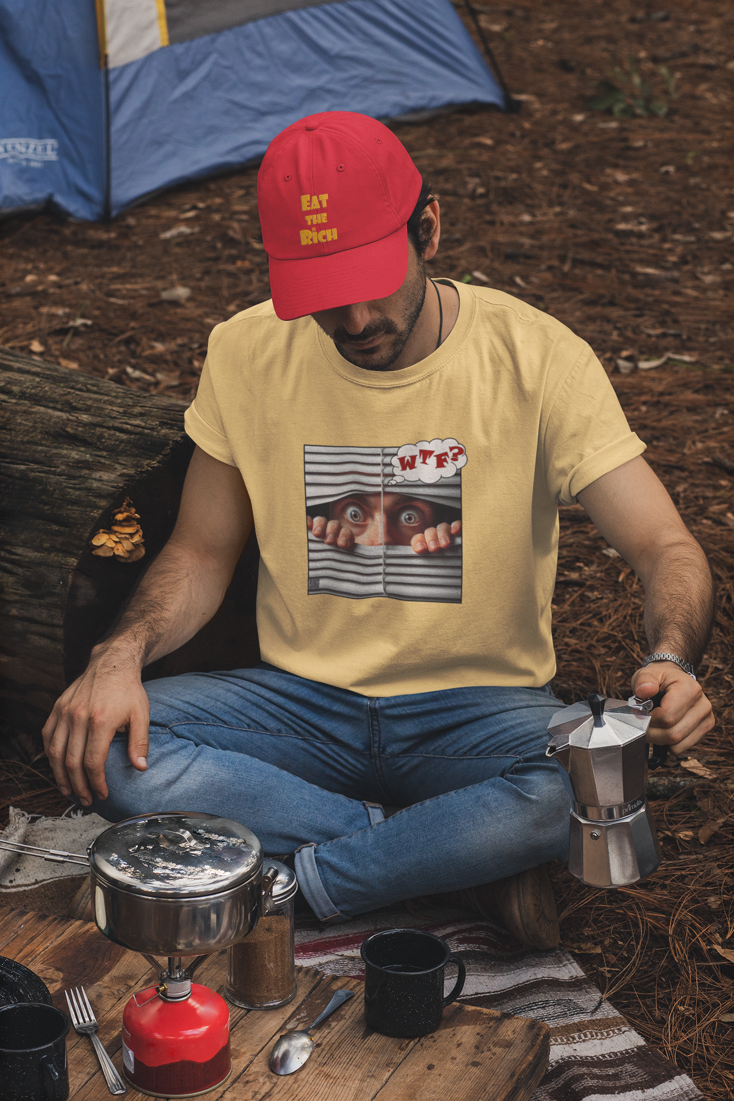 A man in a yellow WTF White Male Model Activist Tshirt and a red cap, sitting outdoors with camping gear.