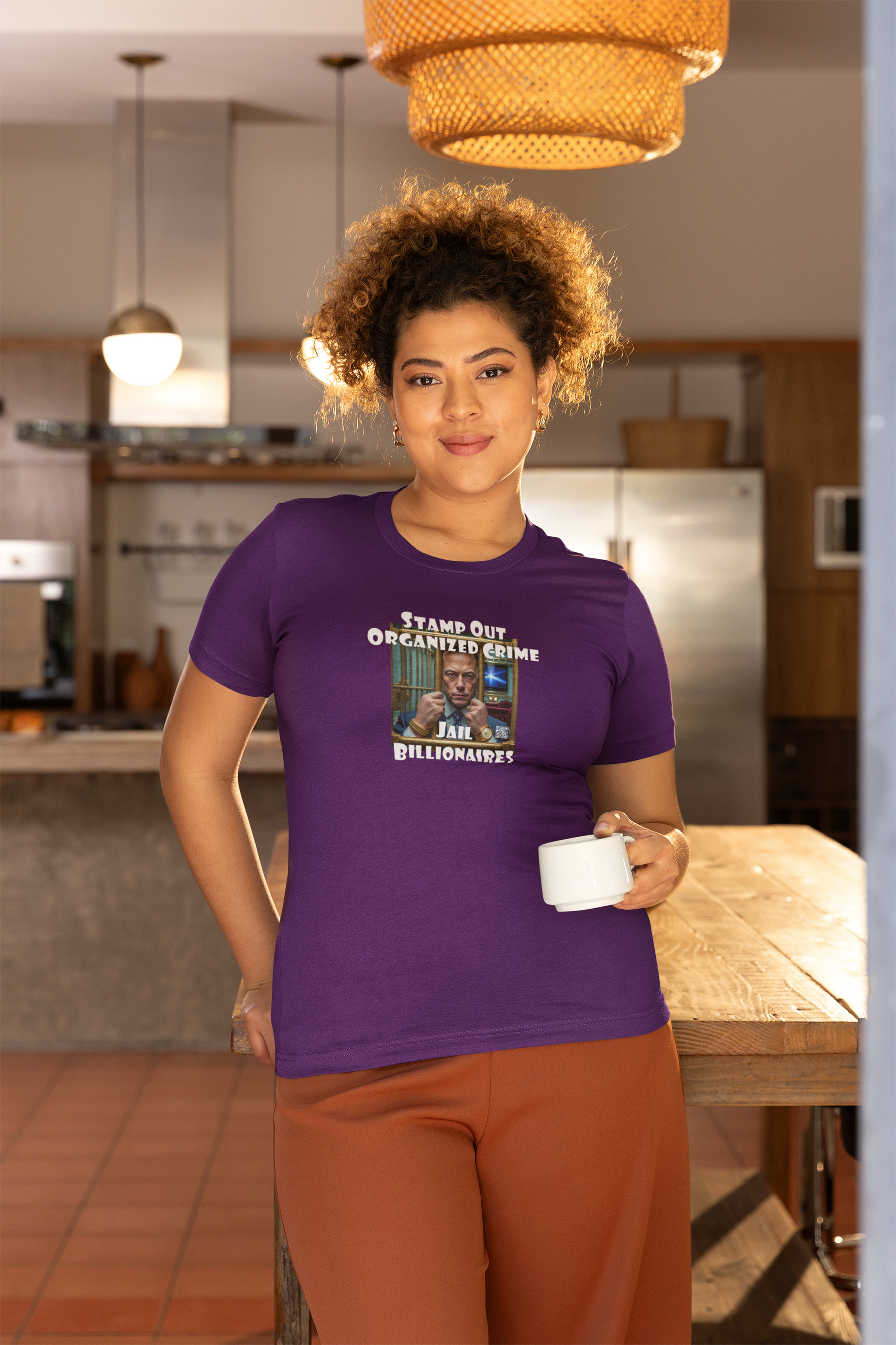 Woman wearing Stamp Out Organized Crime-Jail Billionaires Activist T-shirt in a modern kitchen setting.