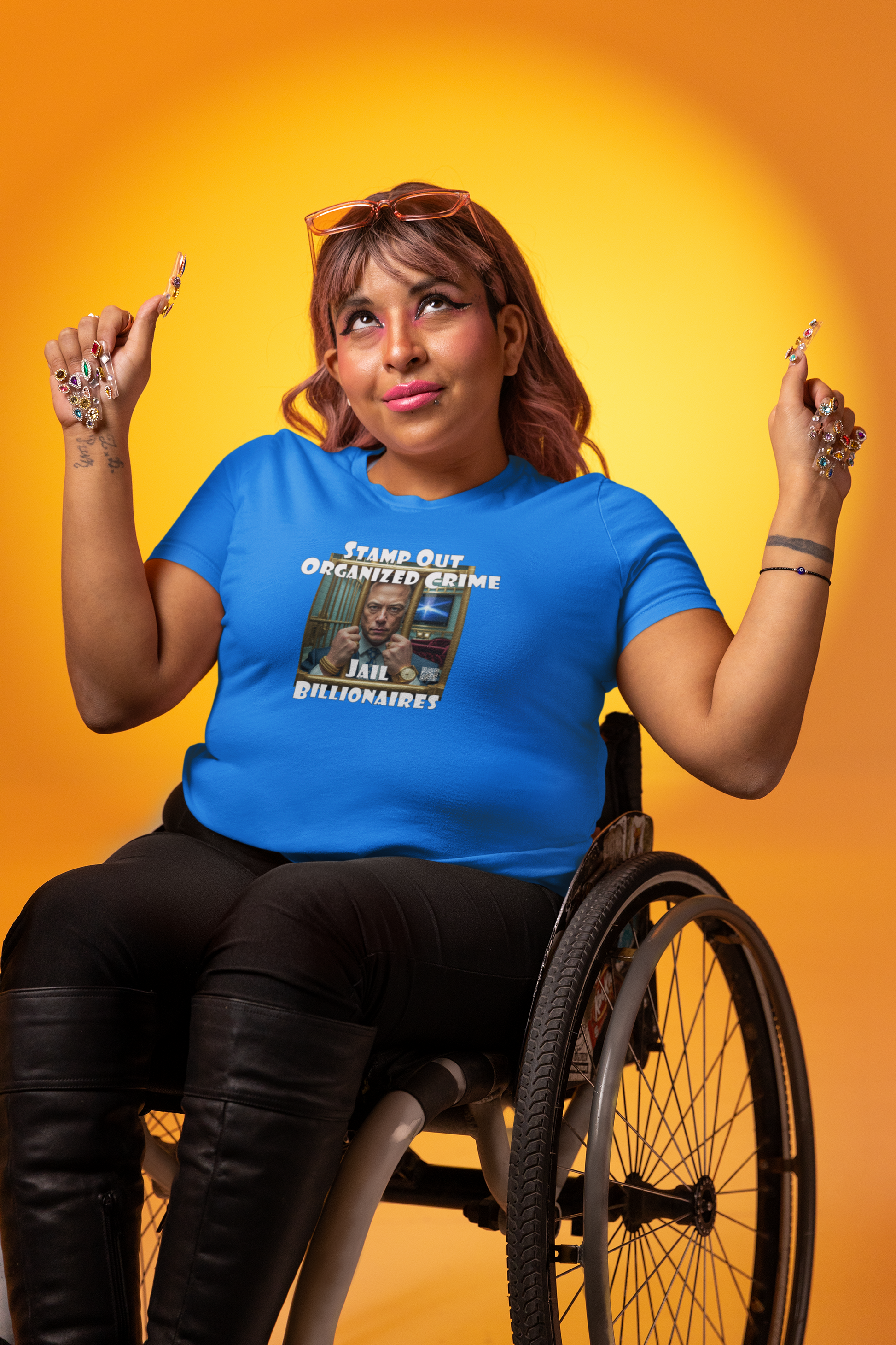 Model in a wheelchair wearing a blue Stamp Out Organized Crime-Jail Billionaires Activist T-shirt, smiling against a yellow backdrop.
