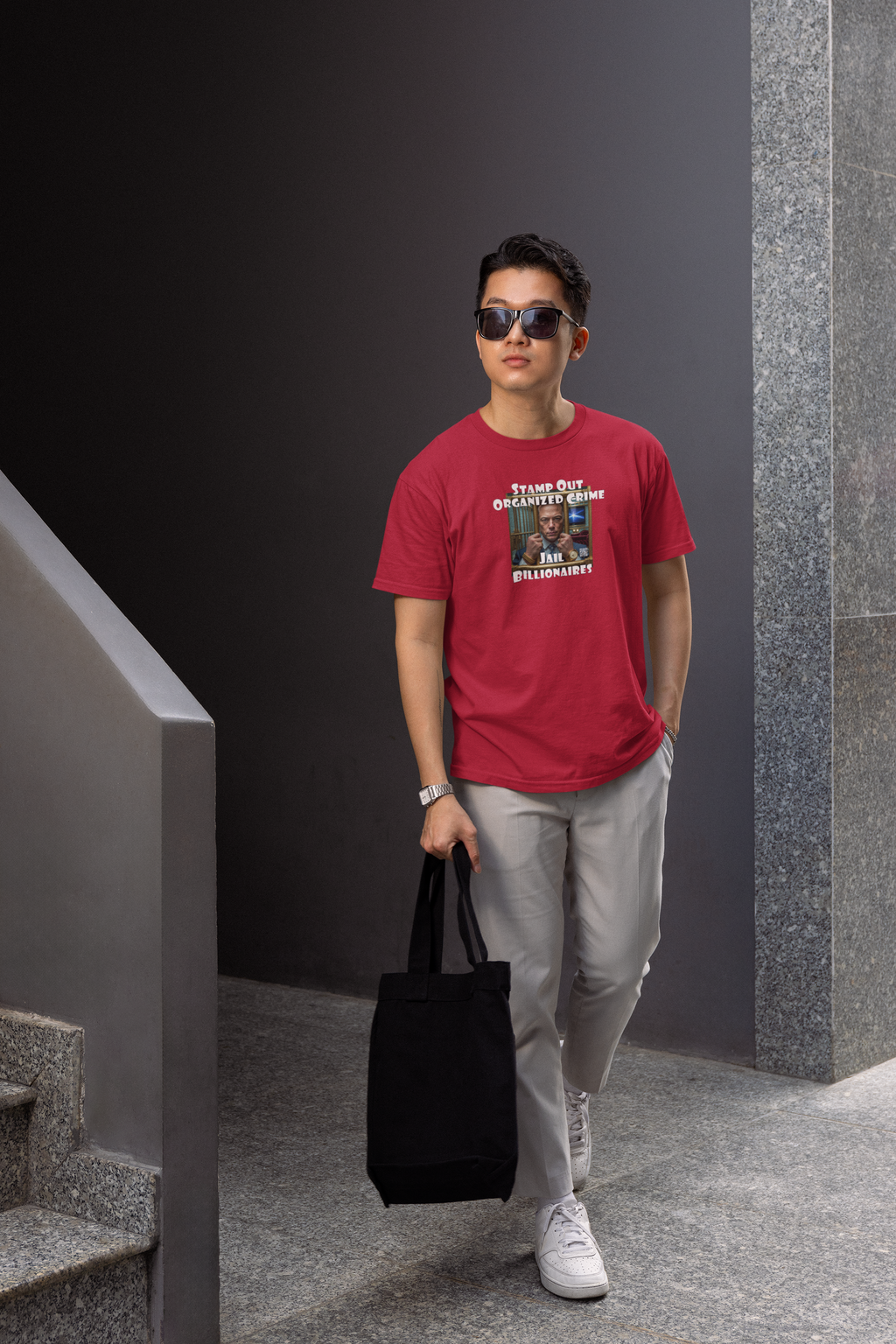 Young man wearing Stamp Out Organized Crime-Jail Billionaires Activist T-shirt, posing with a tote bag.