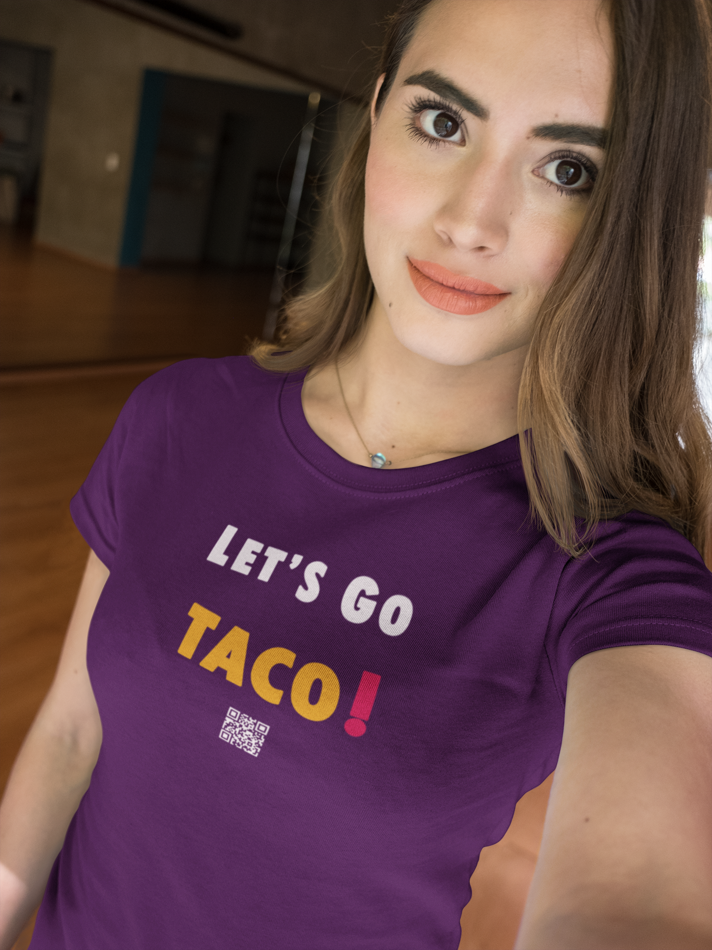 A model wearing a purple TACO Activist TShirt featuring the text 'LET'S GO TACO!' in bold letters.