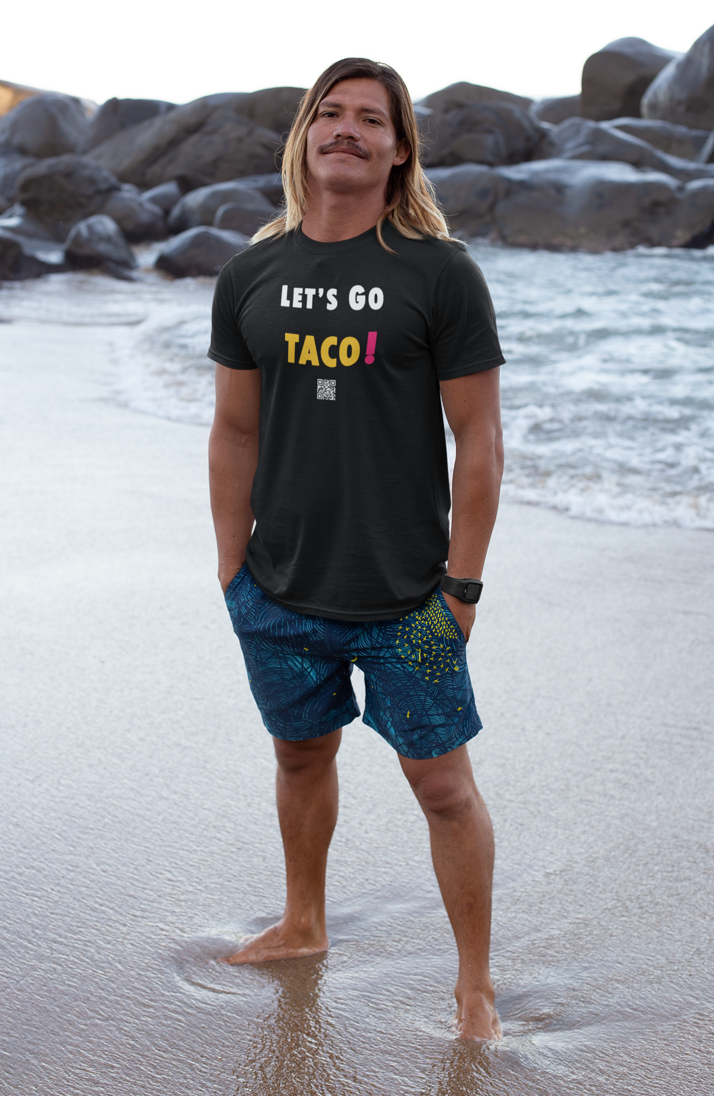 Adult male wearing TACO Activist TShirt at the beach with ocean waves in the background.