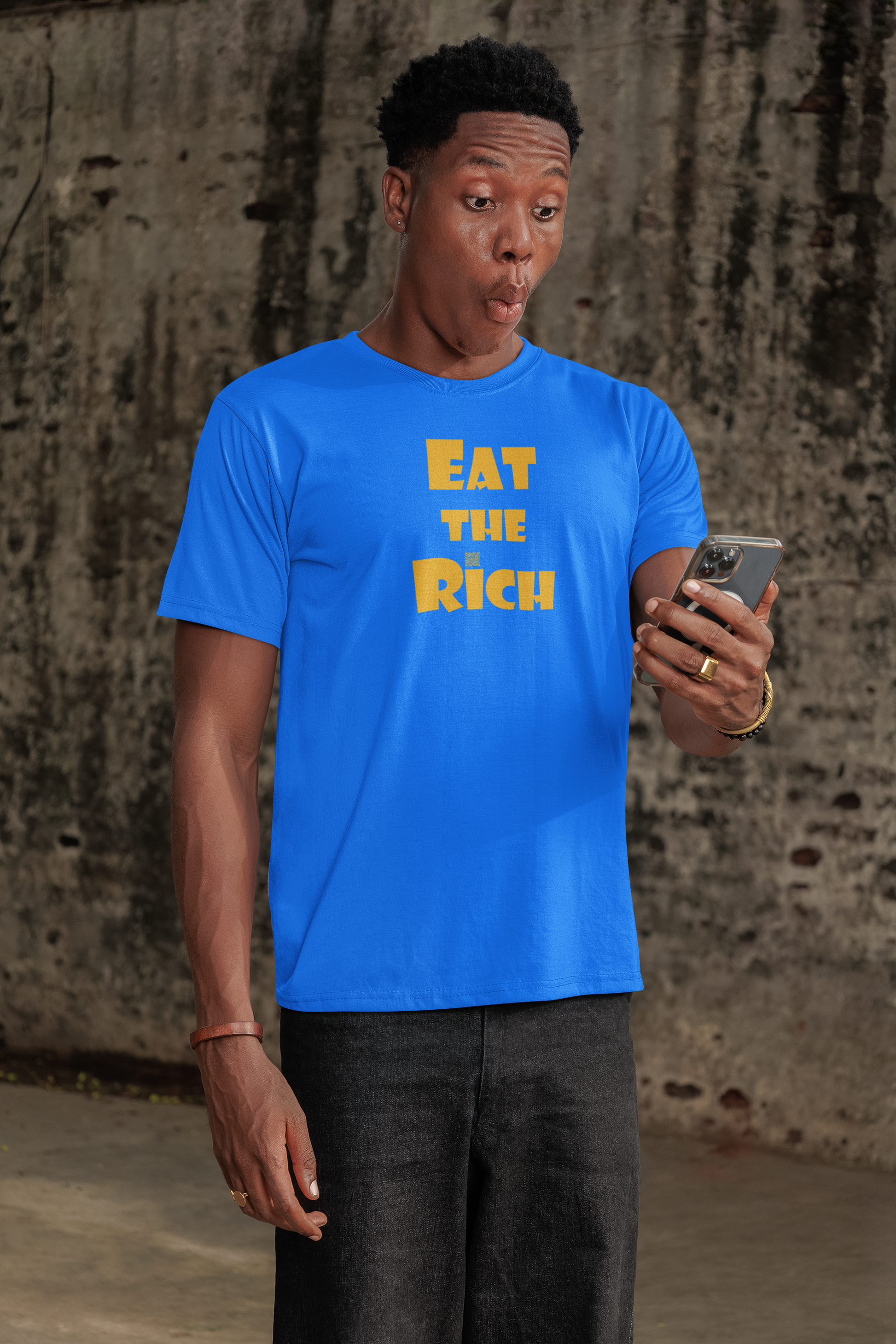 Individual surprised while wearing a blue EAT THE RICH Unisex TShirt, looking at a phone.