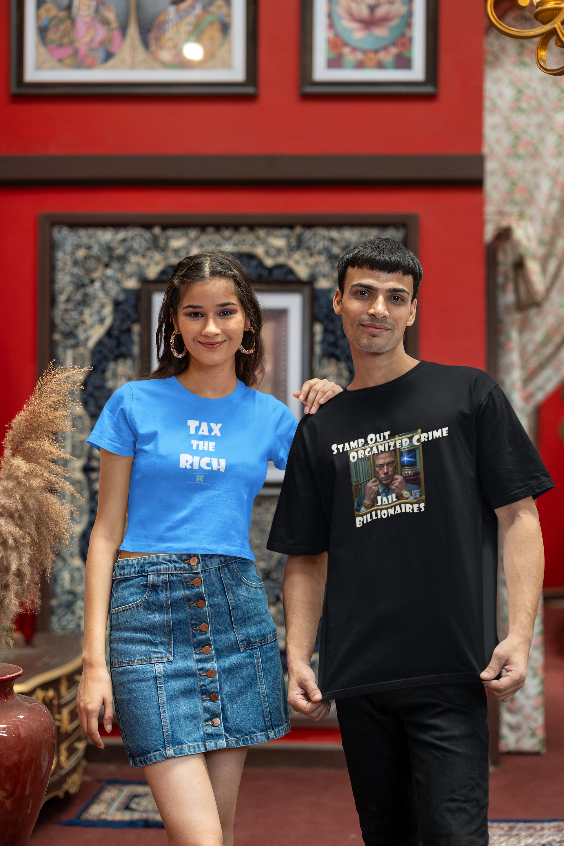 Modeling TAX THE RICH Unisex T-Shirt in blue and black, showcasing bold designs in a vibrant setting.