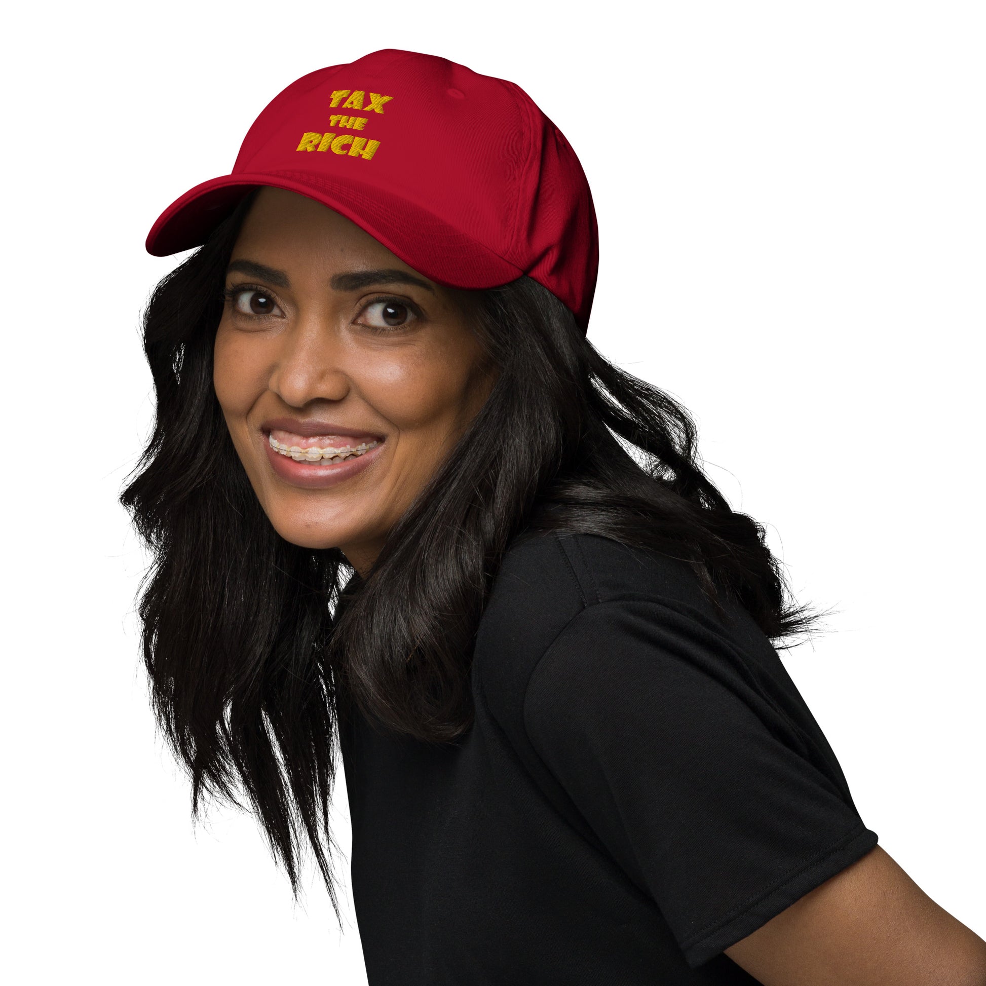 Person wearing a red hat with bold text saying TAX THE RICH — Embroidered Dad Hat.