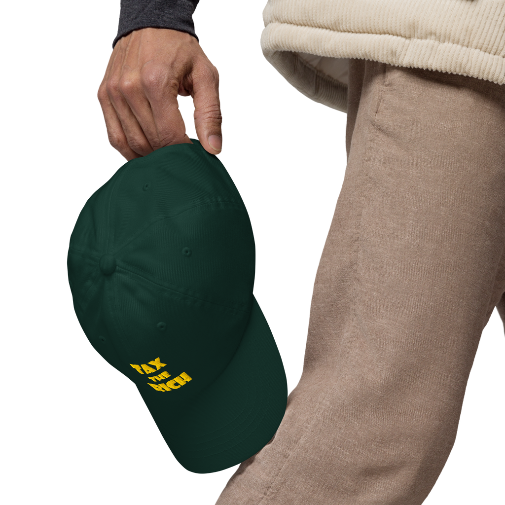 TAX THE RICH — Embroidered Dad Hat being held, featuring bold text design on a dark green background.