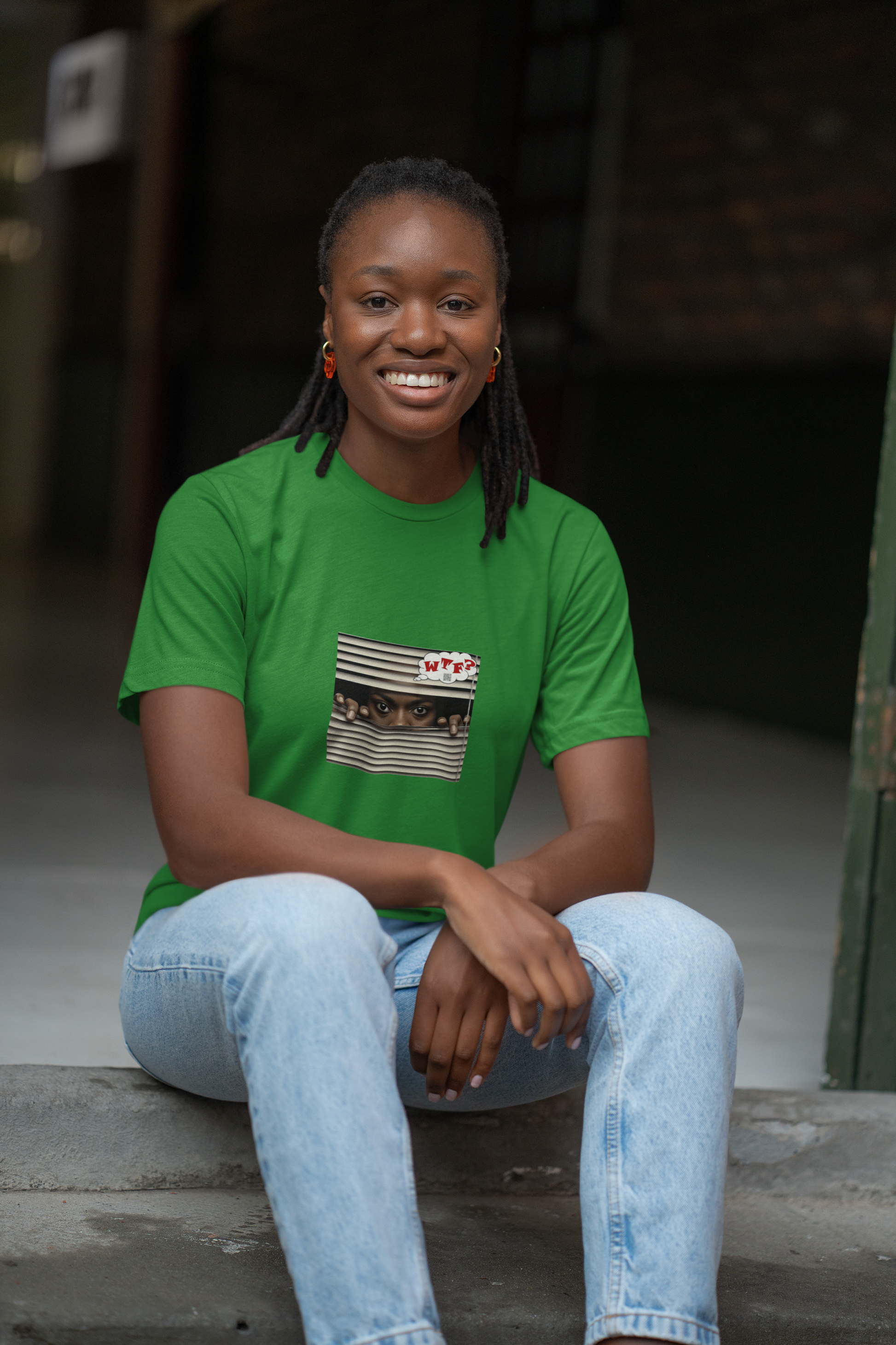 WTF Activist T-Shirt Black Female Model worn by a smiling woman in a green t-shirt sitting on steps.