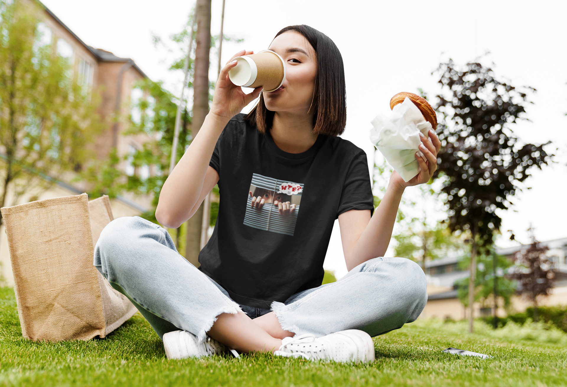 WTF activist t-shirt Asian female model enjoying coffee and a snack on grass outdoors.