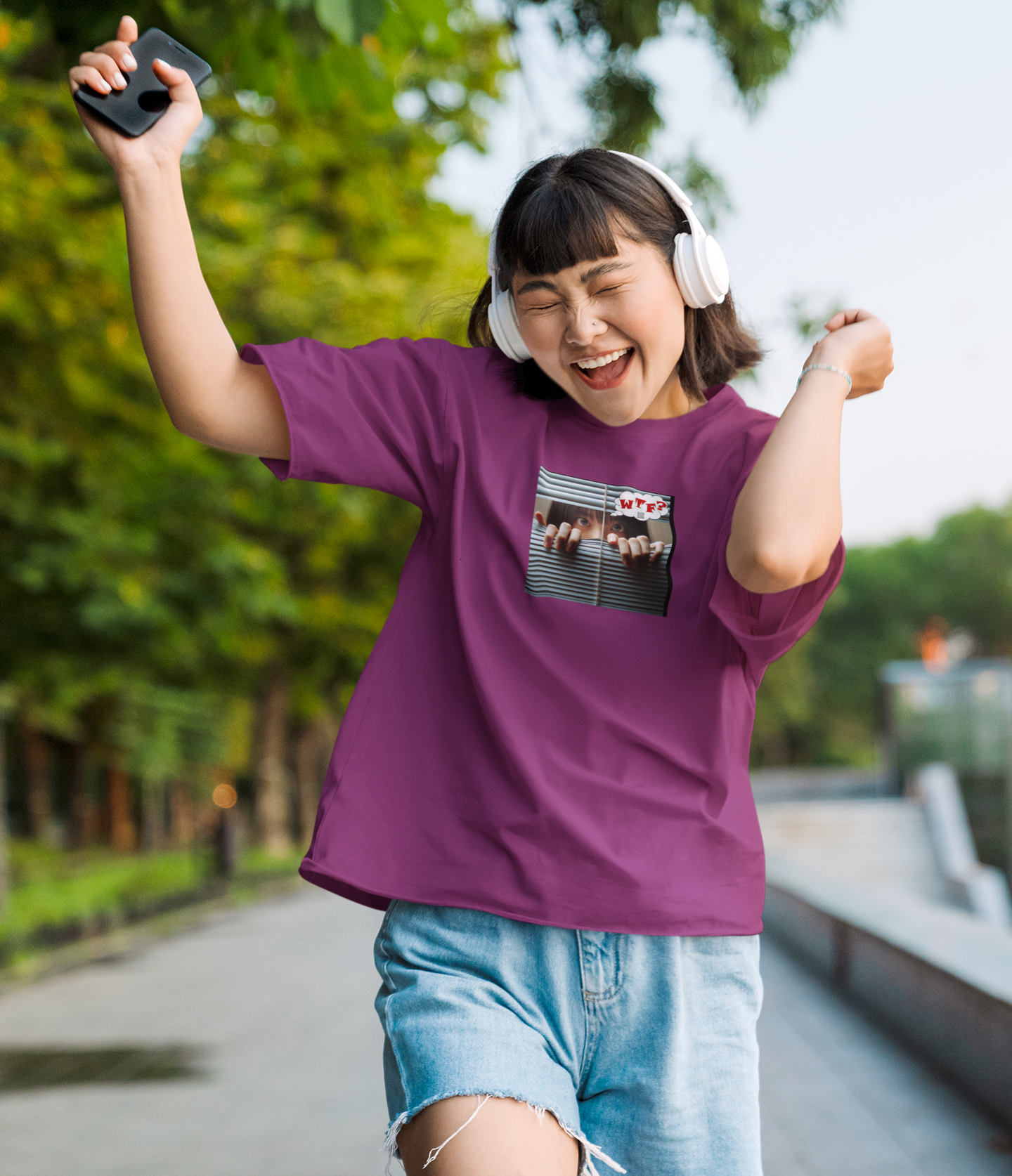 WTF activist t-shirt Asian female model wearing a purple shirt, celebrating outdoors with headphones.