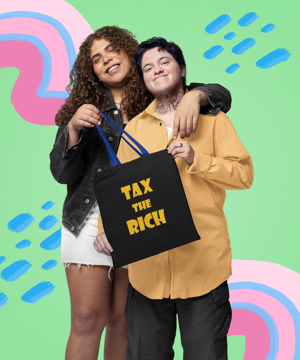 Two people smiling while holding a Tax the Rich accessory tote bag against a colorful background.