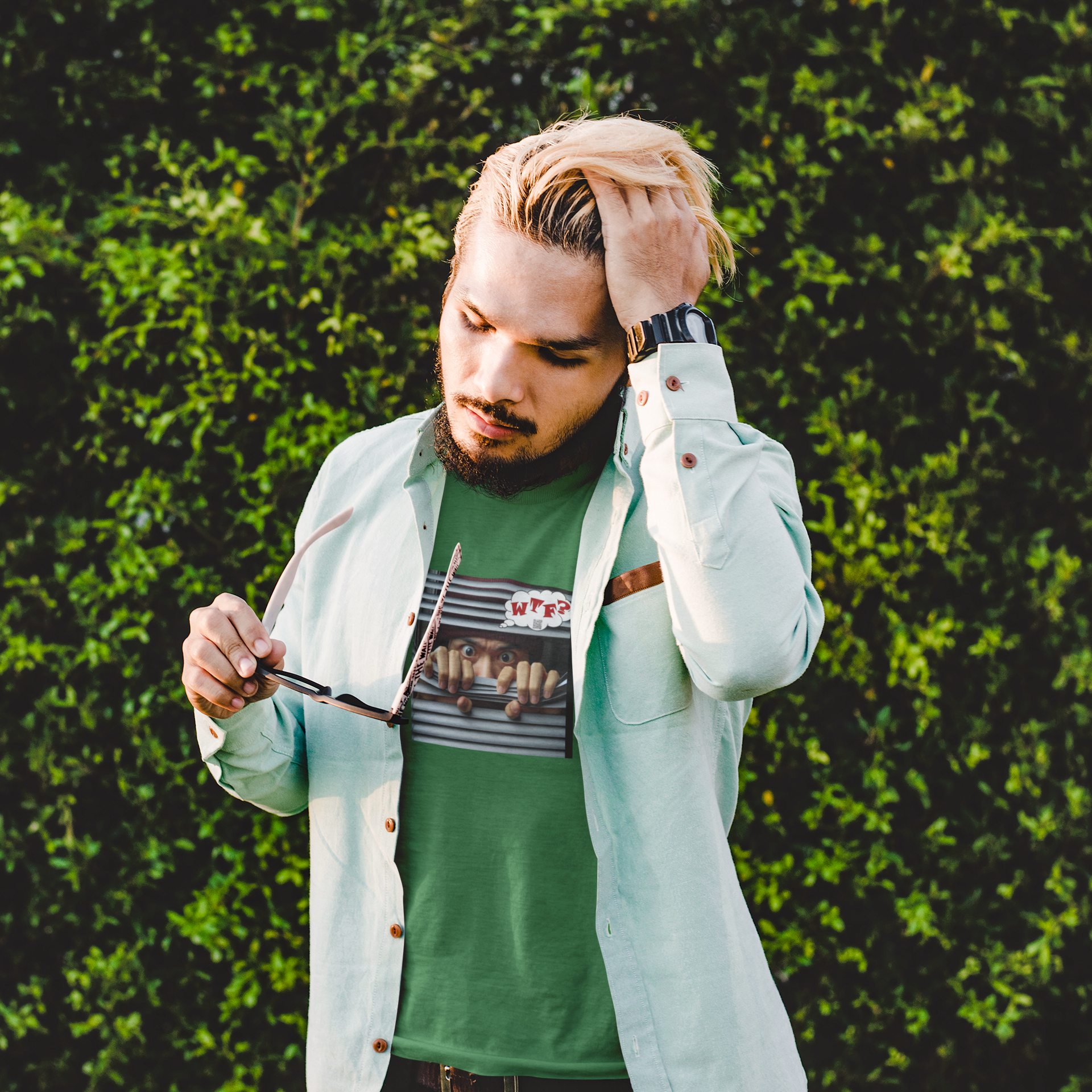 Asian male model wearing WTF activist t-shirt for Asian male model against green foliage background.