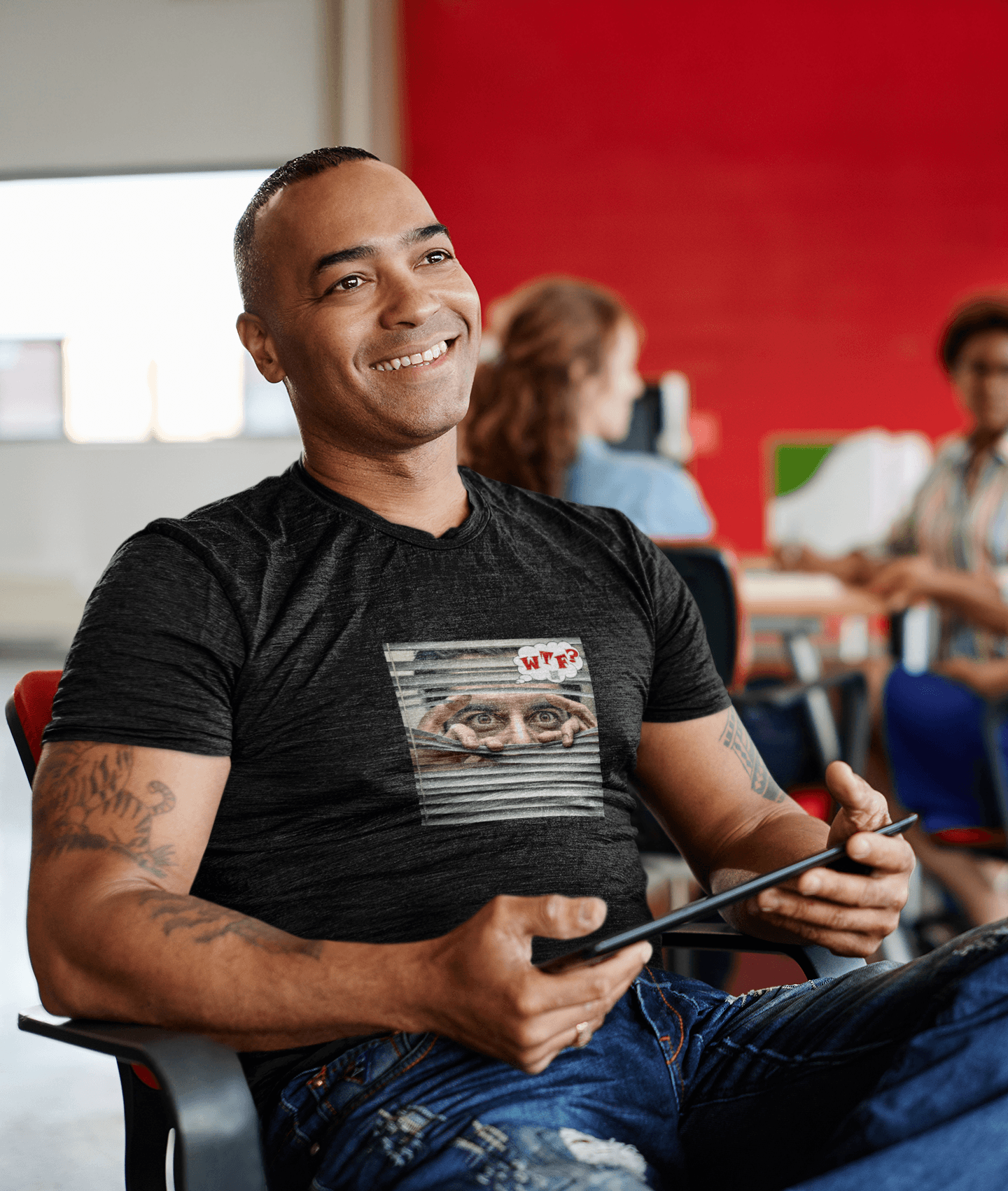 WTF activist t-shirt Hispanic male model wearing a black shirt with a graphic design, smiling while holding a tablet.