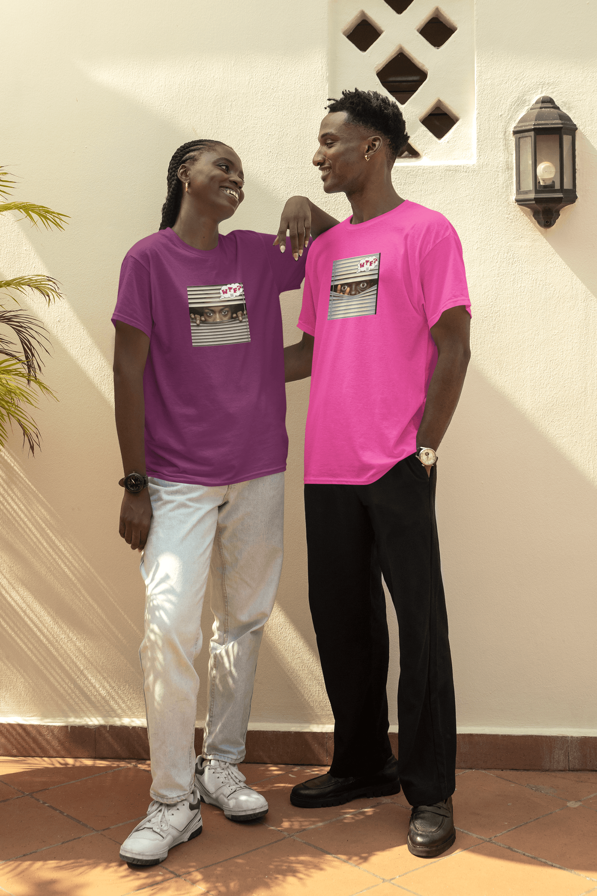 black couple looking longingly at each other. she is wearing a maroon WTF? shirt and he is wearing a heliconia colored unisex WTF? tshirt featuring a black man peering through venetian blinds saying WTF?