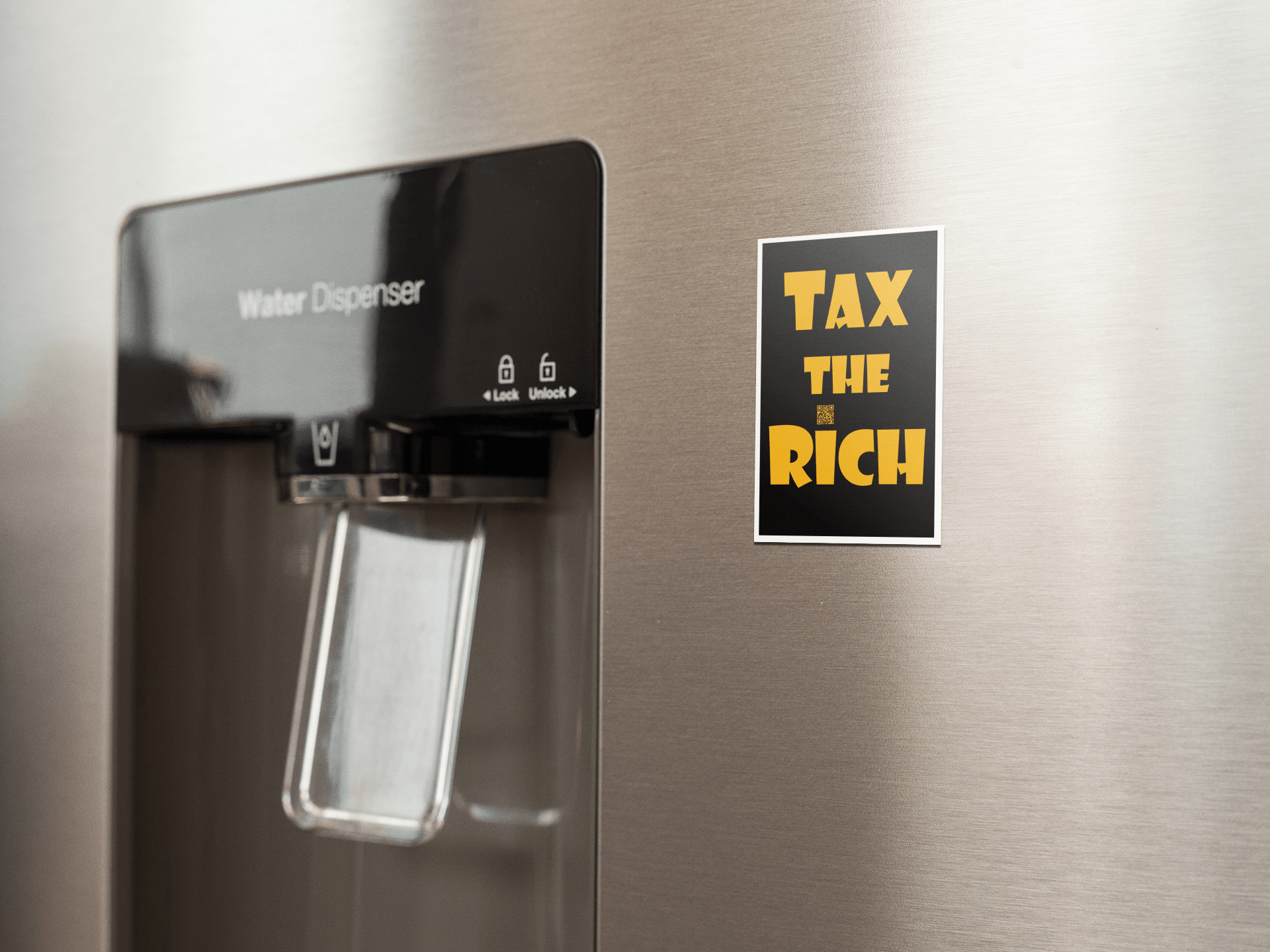 4" x 5" black vinyl magnet with Tax the Rich in gold lettering stuck to the door of a stainless steel refrigerator door