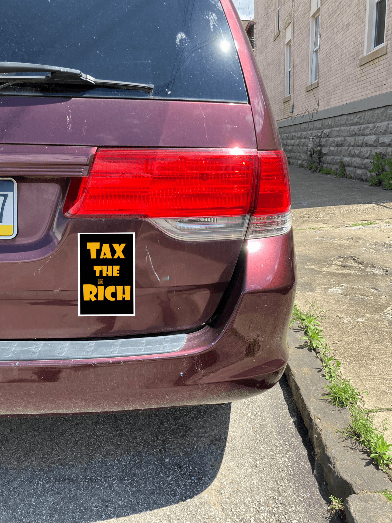 4" x 5" black vinyl magnet with Tax the Rich in gold lettering stuck to the back of a maroon van