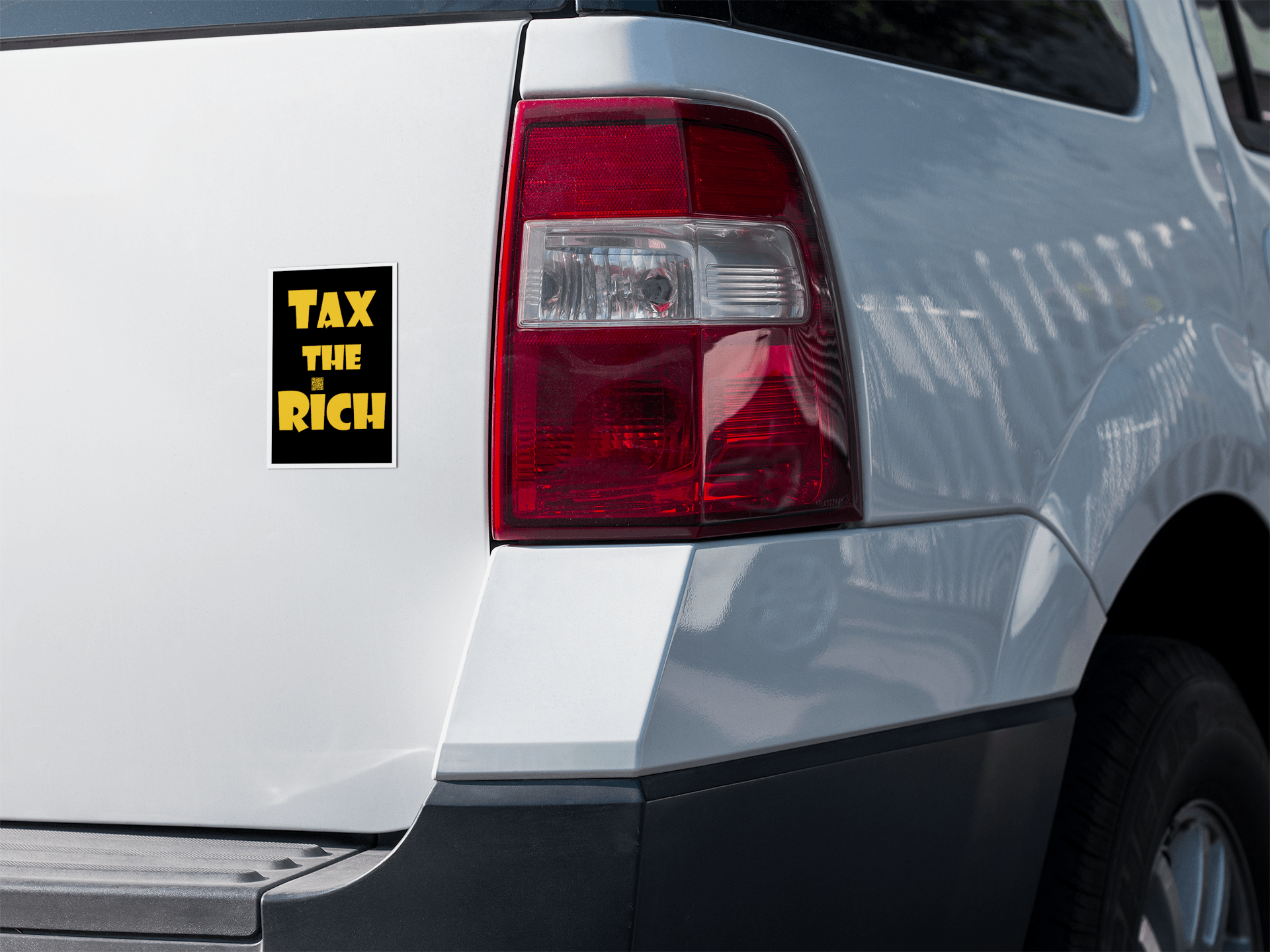4" x 5" black vinyl magnet with Tax the Rich in gold lettering stuck to the back of a white pickup truck