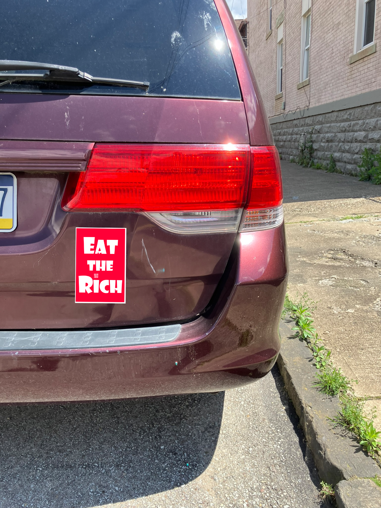 4" x 5" red magnet with white Eat the Rich lettering, on the back of a maroon mini van