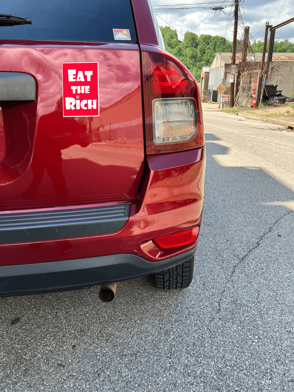4" x 5" red magnet with white Eat the Rich lettering, on the back of a red car