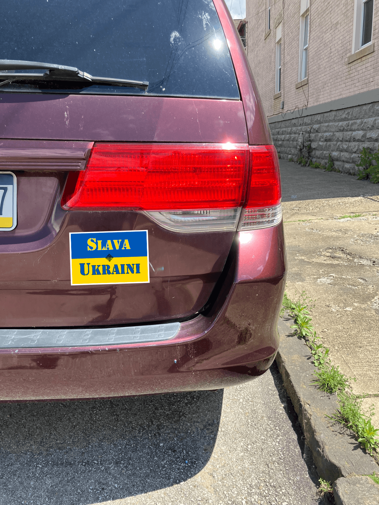 Slava Ukraini magnet displayed on a maroon car, promoting support for Ukraine and democracy.