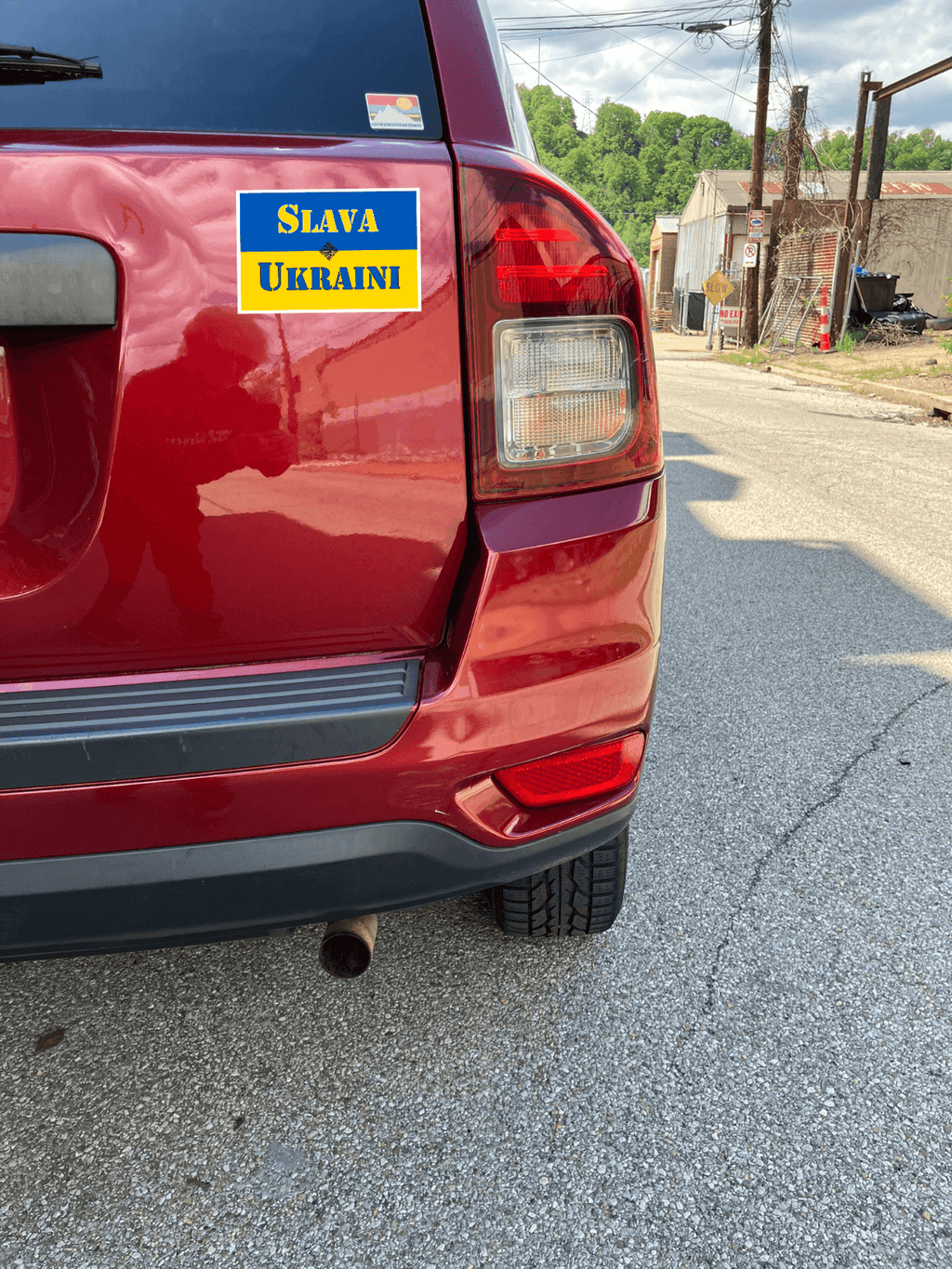 Slava Ukraini magnet displayed on a red car, promoting support for Ukraine and democracy.
