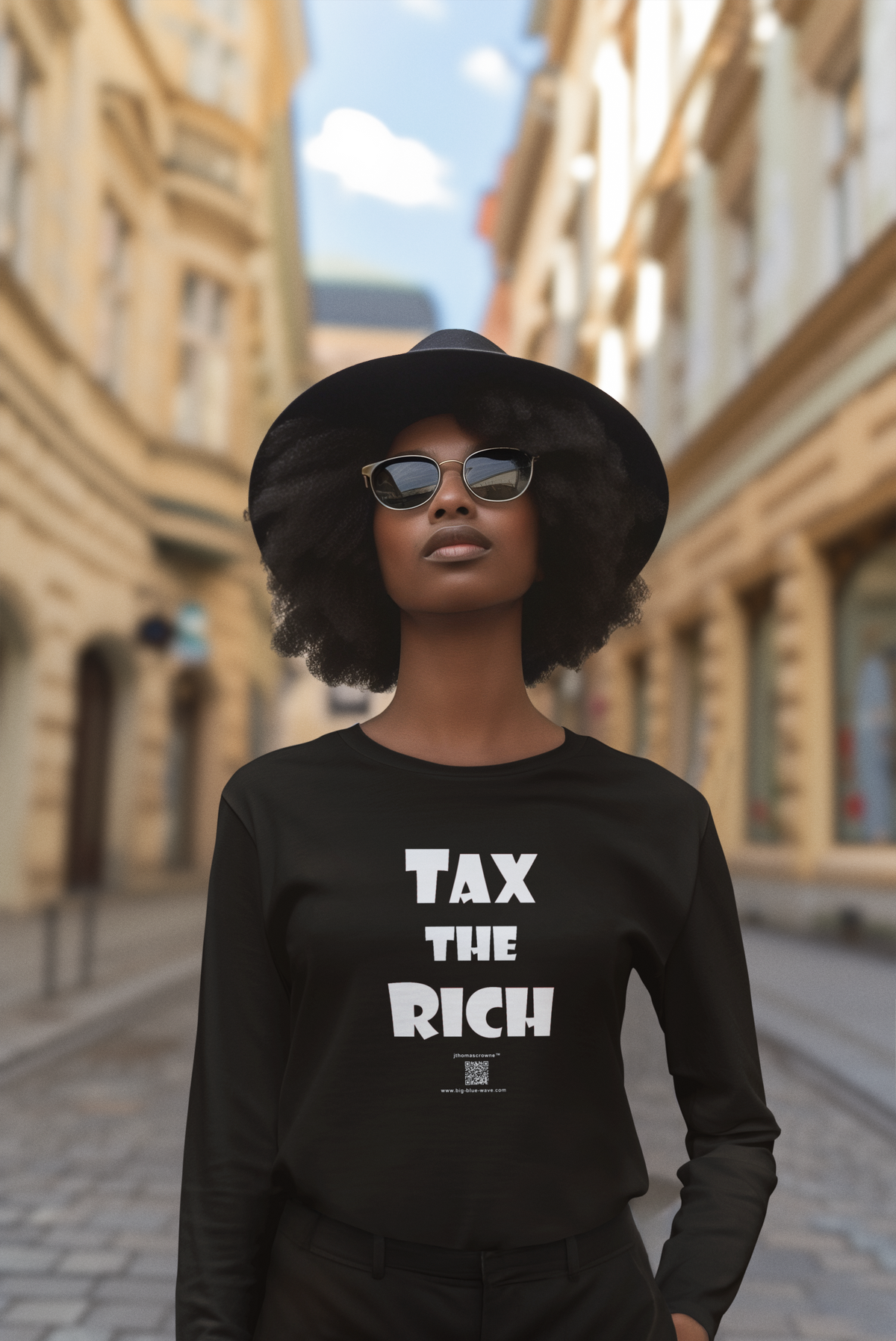 A woman wearing a black wide-brim hat, sunglasses, and a black long-sleeve shirt with the slogan 'TAX THE RICH' printed in bold white letters, standing on a blurred city street.