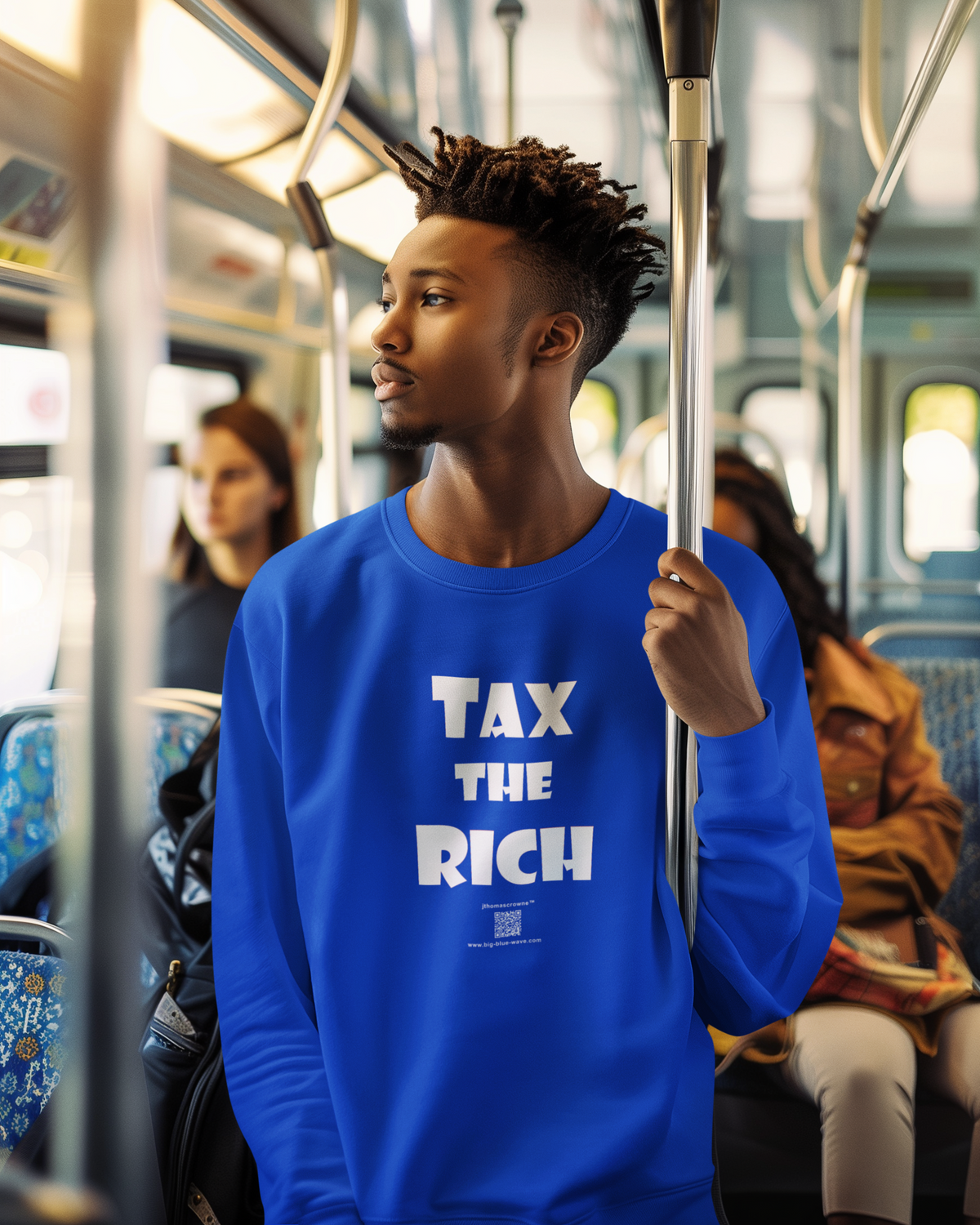 A man standing on a subway train wearing a bright blue crewneck sweatshirt with the slogan 'TAX THE RICH' printed in bold white letters on the front.