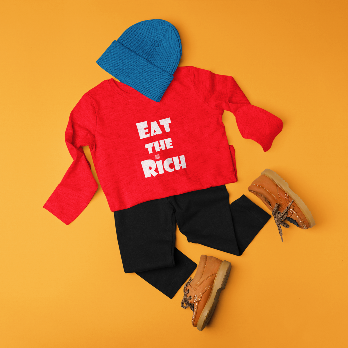 A styled flat-lay outfit set featuring a red long-sleeve shirt with the text 'EAT THE RICH' in white, black leggings, a blue knit beanie, and brown lace-up boots, arranged on a solid orange background.