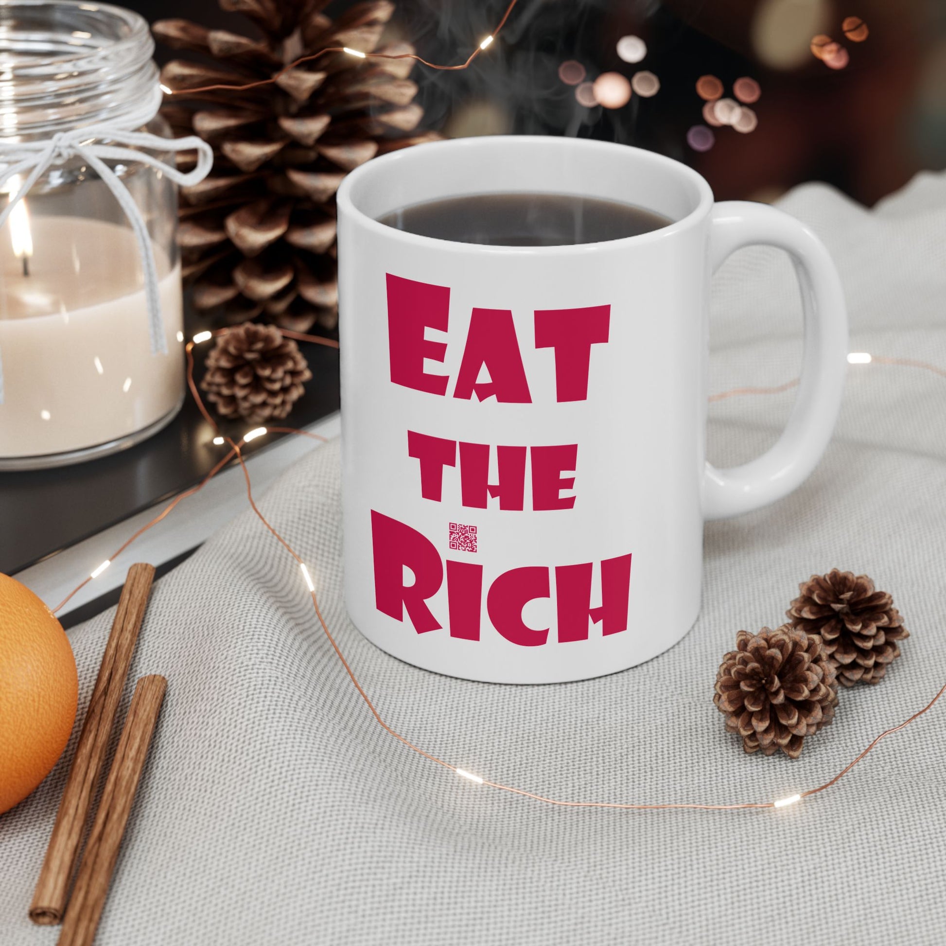 White EAT THE RICH 11oz Ceramic Mug featuring bold red text on a stylish table setting.